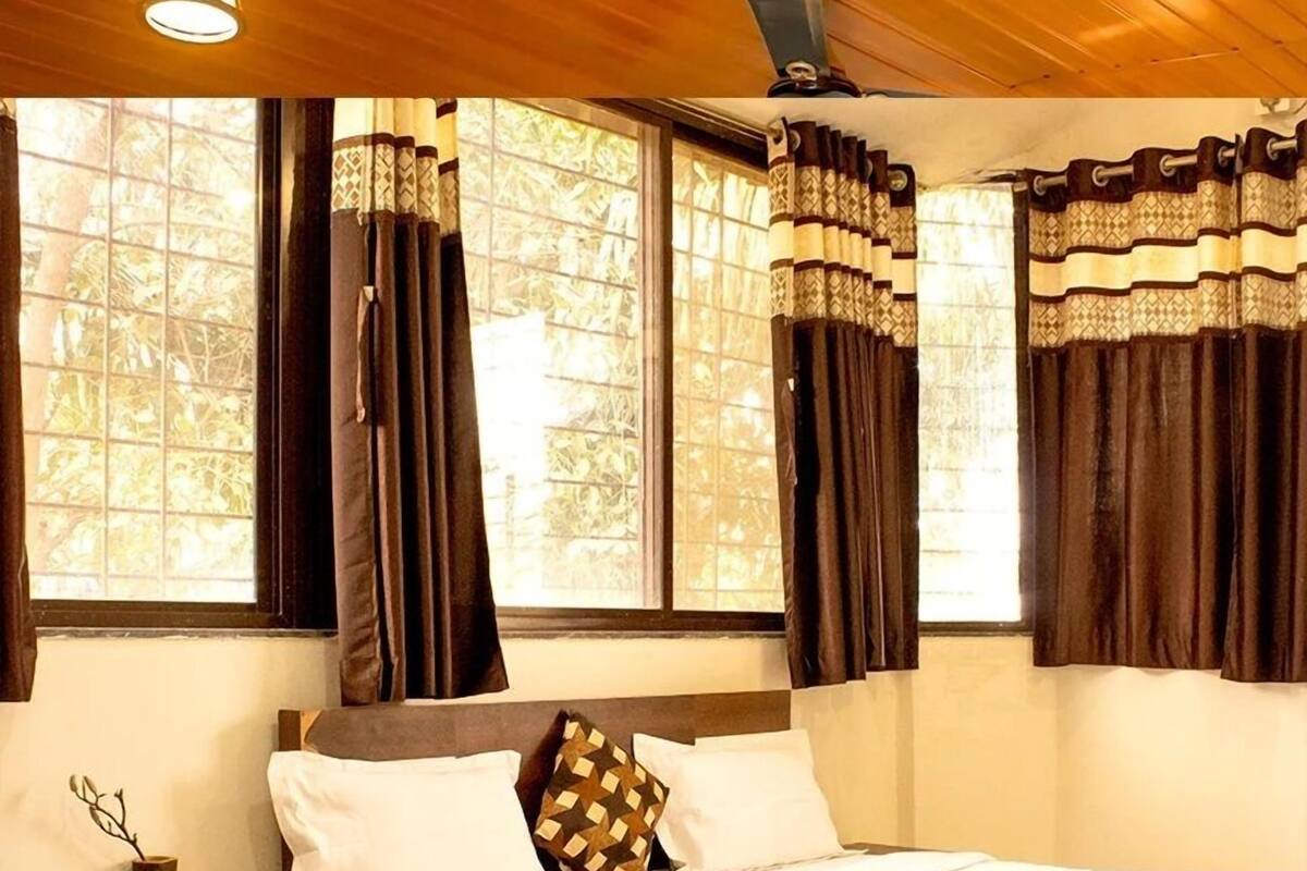 A bedroom with a bed, nightstand, and window with curtains.