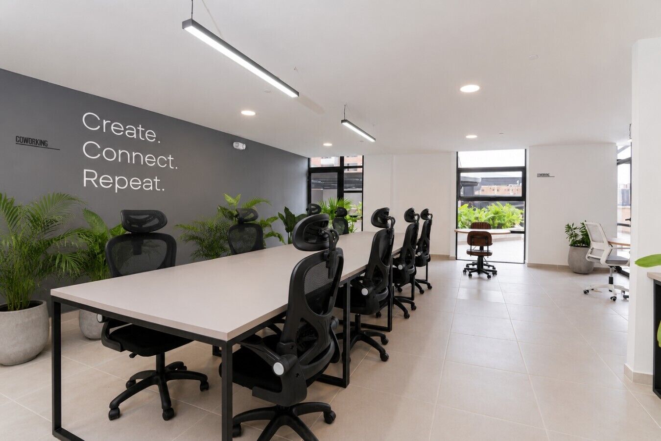 A modern office space with a long table and chairs, potted plants, and a motivational wall.