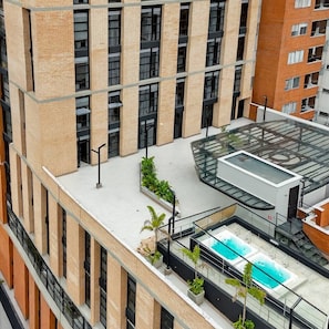 A high-rise building with a rooftop pool area, large windows, and a modern architectural design.