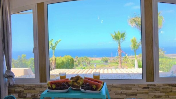 A table with fruit and drinks by a large window overlooking a coastal view. - Exclusive Golf Villa (Private Swimming Pool) Costa Adeje (Adeje)