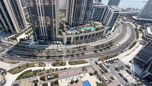 A high-rise residential building with a central courtyard, a swimming pool, and a landscaped area with palm trees.