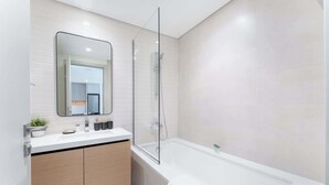 A modern bathroom with a white vanity, a large mirror, and a glass-enclosed shower.