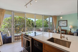 A modern kitchen with a large island, stainless steel appliances, and a view of the outdoors. - Gorgeous Oceanfront Condo! - Kamaole Nalu #202 (Kihei, Maui)