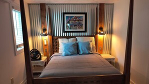 A neatly arranged bedroom with a wooden bed, two bedside tables, a framed picture above the bed, and a window with blinds. - Three-bedroom cottage on Little Glen Lake (Empire)