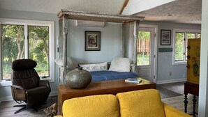 A bedroom with a bed, a chair, a sofa, and a large vase. - Three-bedroom cottage on Little Glen Lake (Empire)