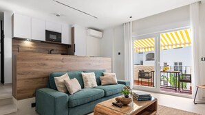 Un salon moderne avec un canapé de couleur turquoise, une table basse en bois et une vue sur le balcon extérieur.
