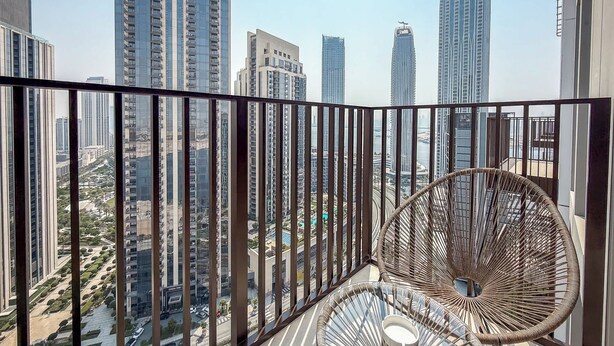 A balcony with a view of high-rise buildings and a wicker chair.