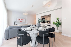 A modern dining area with a marble table, black chairs, and a grey sofa.