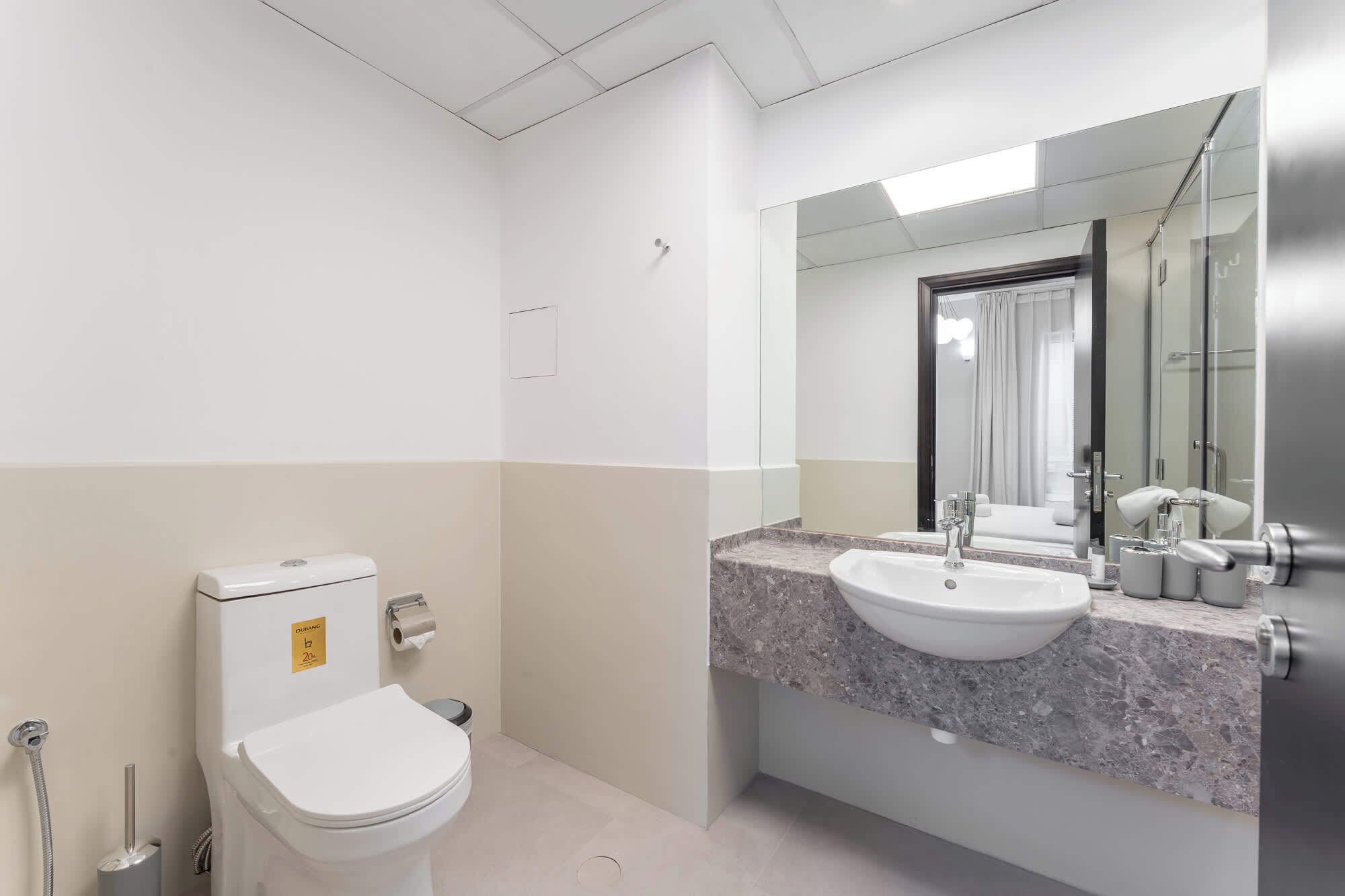 Et stilfuldt badeværelse med toilet, vask og spejl.