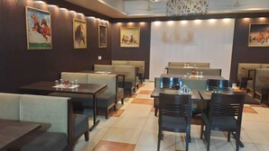 A restaurant with booths and tables, featuring artwork on the walls. - Hotel O Hari Villa (Jaipur)