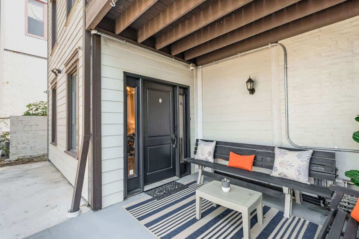 A covered porch with a bench, a door, and a wall-mounted light fixture.