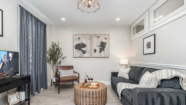 A living room with a sofa, a coffee table, a TV, and artwork on the wall.