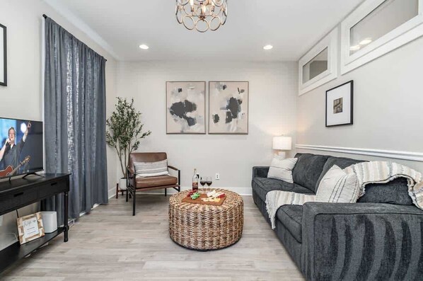 A living room with a sofa, a coffee table, a TV, and artwork on the wall.