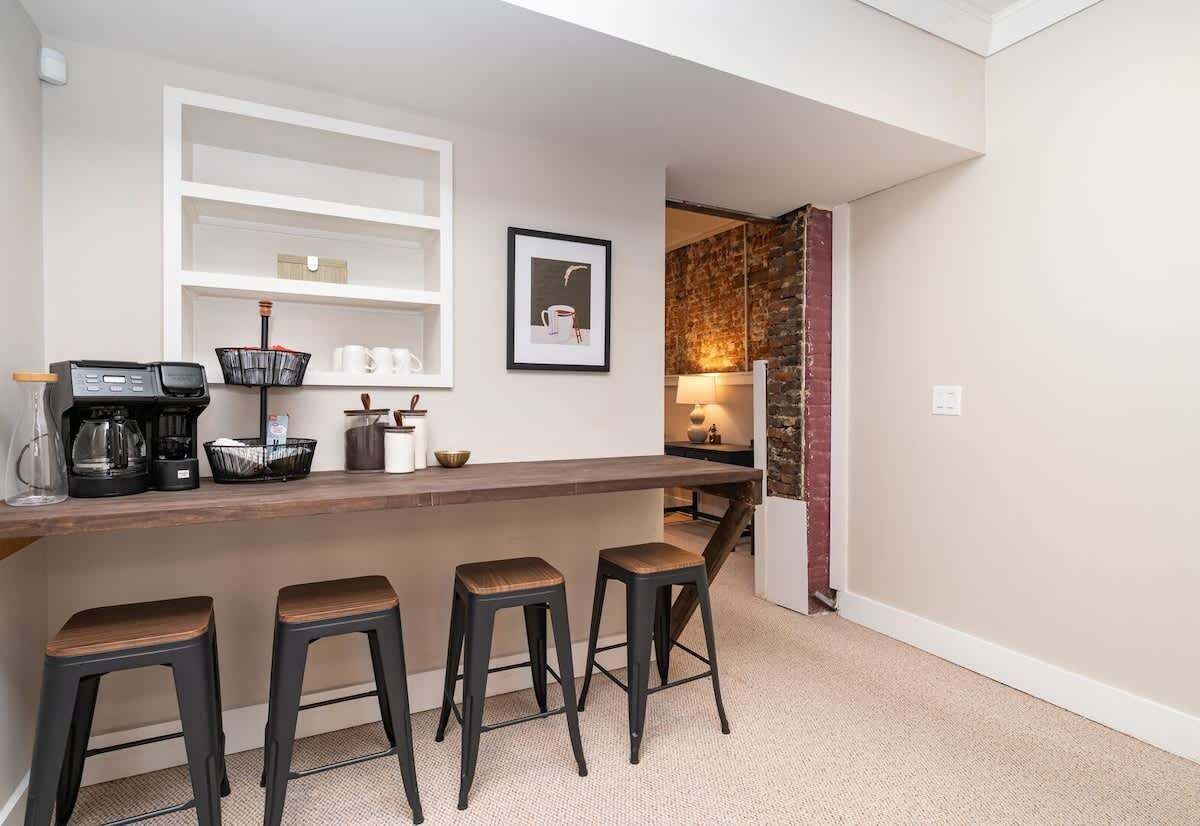 Eine Küche mit Barbereich, Hockern, einer Kaffeemaschine und einem gerahmten Bild an der Wand.