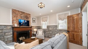 A living room with a fireplace, a television, a sofa, and a wooden door.