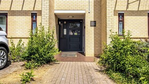 A brick building with a black door, a small entrance, and a sign indicating the address.