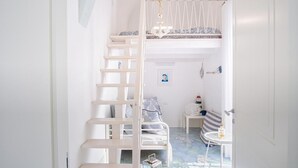 Un intérieur blanc avec un lit superposé, une petite table et une chaise.