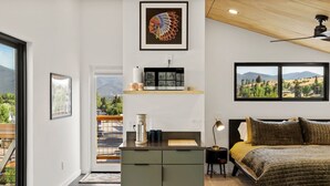 A modern bedroom with a bed, a desk, and a view of the outdoors.