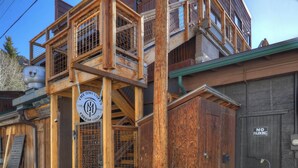 A wooden building with a sign indicating 'The OMI Lofts' and 'CREO DE COLD' with a metal gate and stairs.