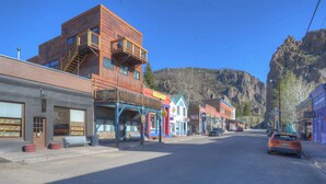 A street with buildings, a car, and a mountain in the background.