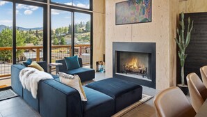 A modern living room with a fireplace, large windows, and a view of the outdoors.