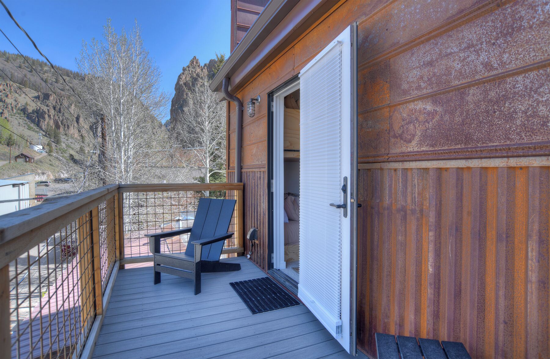 Una terraza de madera con una silla, una puerta y vistas a un paisaje montañoso.