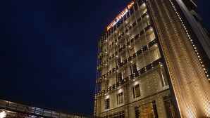 A multi-story hotel with illuminated signage and string lights. - Hotel Status Inn (Ambernath)