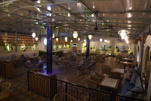A spacious indoor dining area with multiple seating arrangements, including tables and chairs, and a central decorative pillar.