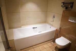 A bathroom with a bathtub, toilet, and a shower. - Hotel Status Inn (Ambernath)