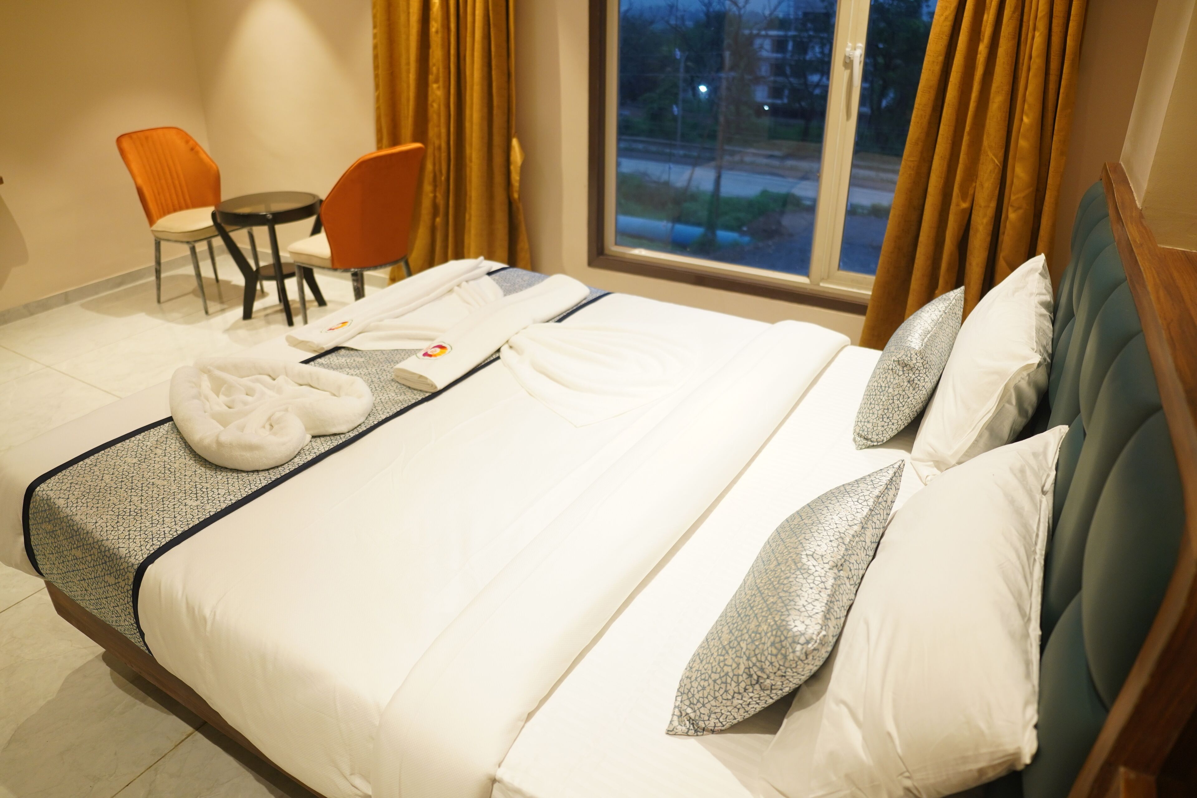 Ein Hotelzimmer mit einem Bett, zwei Stühlen, einem Tisch und einem Vorhangfenster.