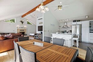 Eine moderne Küche mit weißen Schränken, einem Edelstahl-Kühlschrank und einem Essbereich mit Holztisch und Korbstühlen.