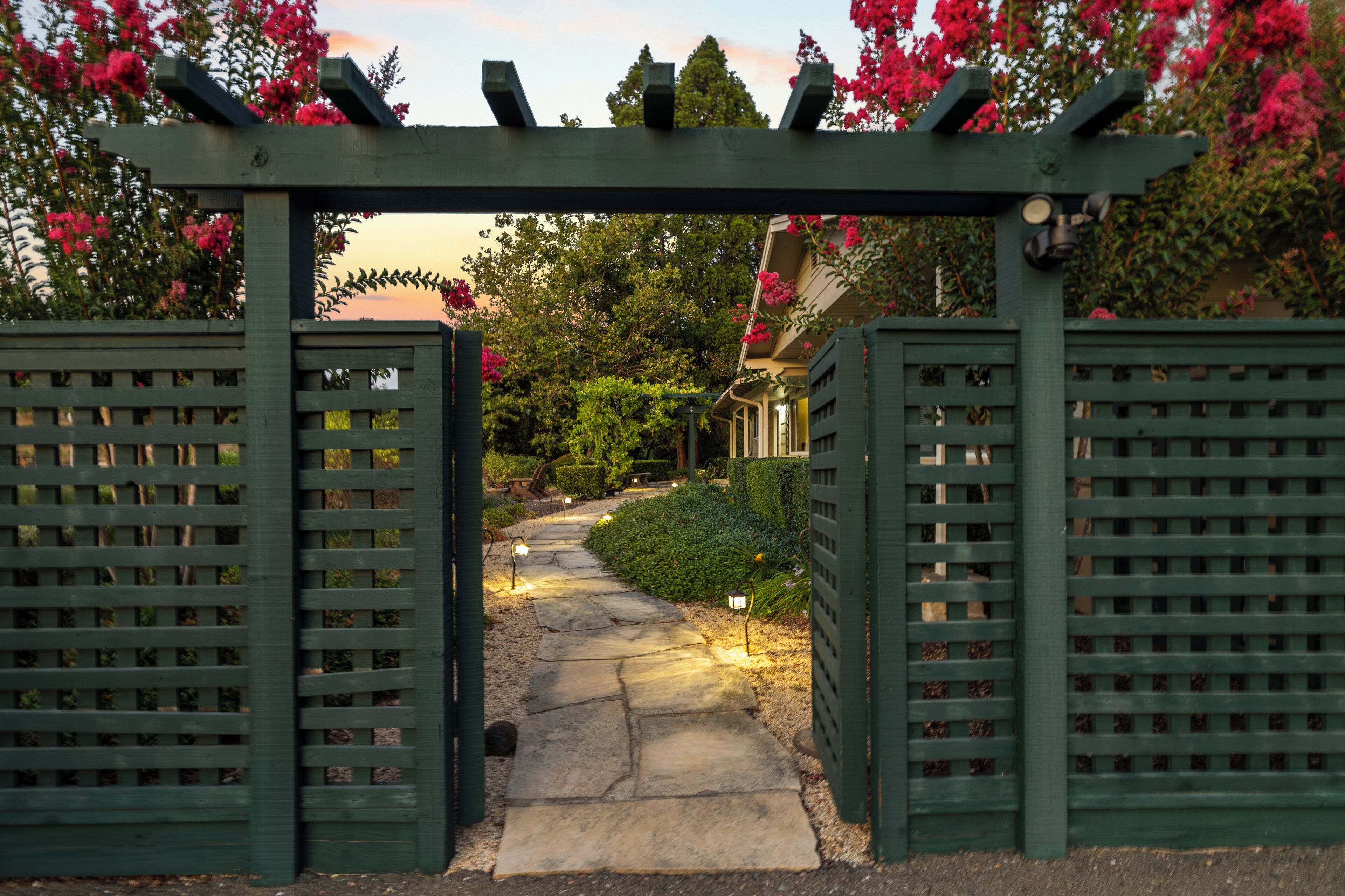 A garden pathway leading to a building with a pergola entrance.