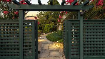 A garden pathway leading to a building with a pergola entrance.
