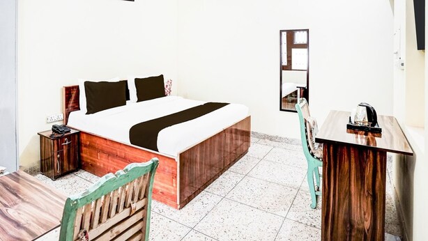 Una habitación de hotel con cama, escritorio, silla, espejo y obras de arte en la pared.