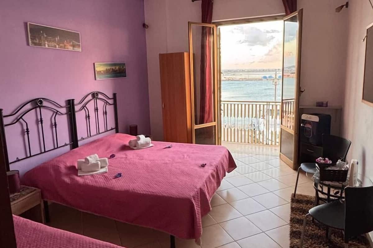 Una habitación con dos camas, un escritorio y vista al mar.