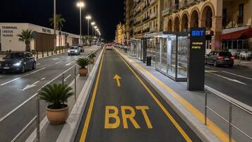 A nighttime street with a BRT bus lane, a bus stop, and buildings with balconies.