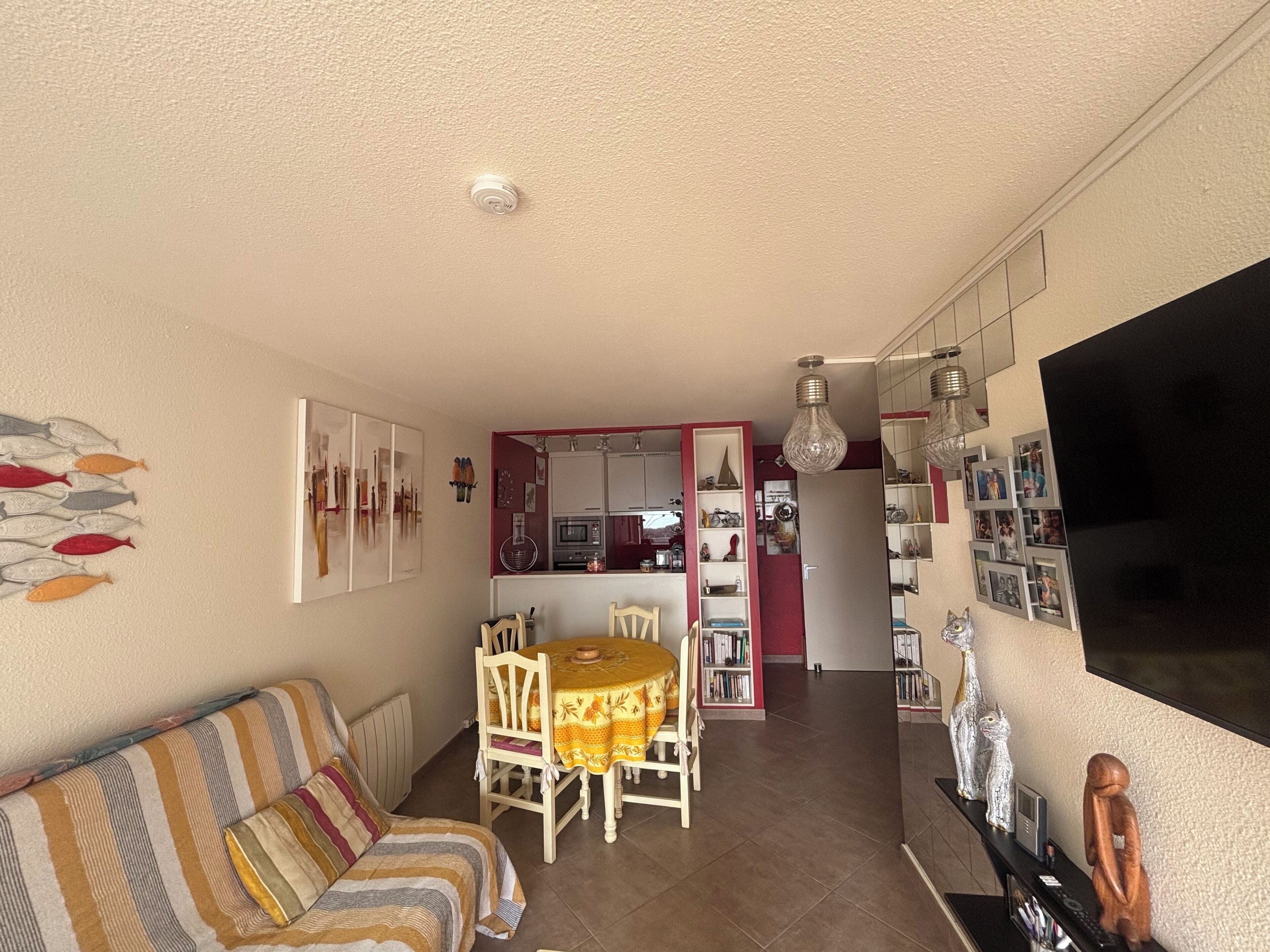 Una sala de estar acogedora con sofá, mesa de comedor y sillas. Cuenta con una zona de cocina, armarios y un microondas.