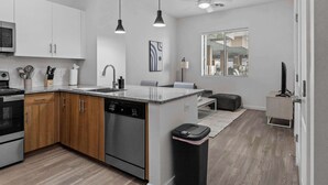 A modern kitchen with white cabinets, a dishwasher, and a wooden countertop.