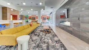 A modern lobby with a yellow sofa, a white coffee table, and a patterned rug. - Boulevard Stays Modern Tempe 1BR ASU Pool, Gym 08 (Tempe)