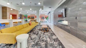 Un vestíbulo moderno con un sofá amarillo, una mesa de centro blanca y una alfombra estampada.