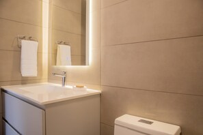 Un baño moderno con un lavabo blanco, un espejo y un inodoro.