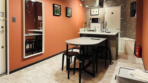 Una cocina compacta con comedor, microondas, estufa a gas y refrigerador pequeño.