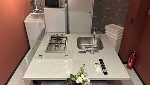 Una cocina compacta equipada con estufa a gas, lavamanos, microondas y un refrigerador pequeño.