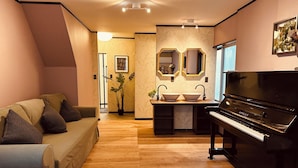 Una sala de estar moderna con un piano, un sofá, una mesa de centro y una zona de lavamanos con dos espejos.