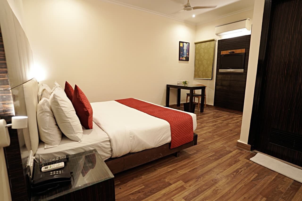 A hotel room with a bed, bedside table, and a small table with a chair.