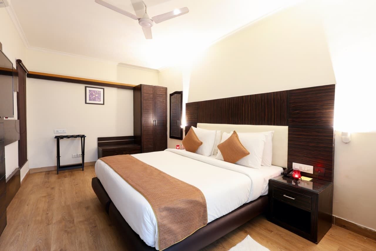 A hotel room with a bed, bedside table, nightstand, and a ceiling fan.