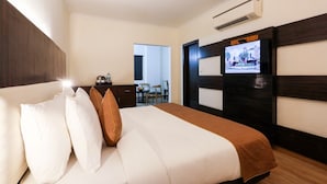 Une chambre d’hôtel équipée d’un lit, d’oreillers, d’un téléviseur mural, d’un bureau avec une chaise et d’un appareil de climatisation.