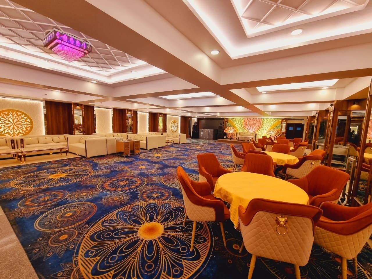 A hotel lobby with a patterned carpet, seating areas, and a chandelier.