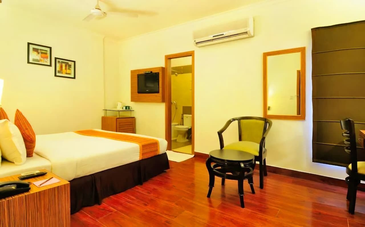 Une chambre d’hôtel équipée d’un lit, d’une chaise, d’un bureau, d’un miroir et d’un appareil de climatisation.