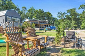 A wooden deck with Adirondack chairs, a small table, and a tiki lamp.